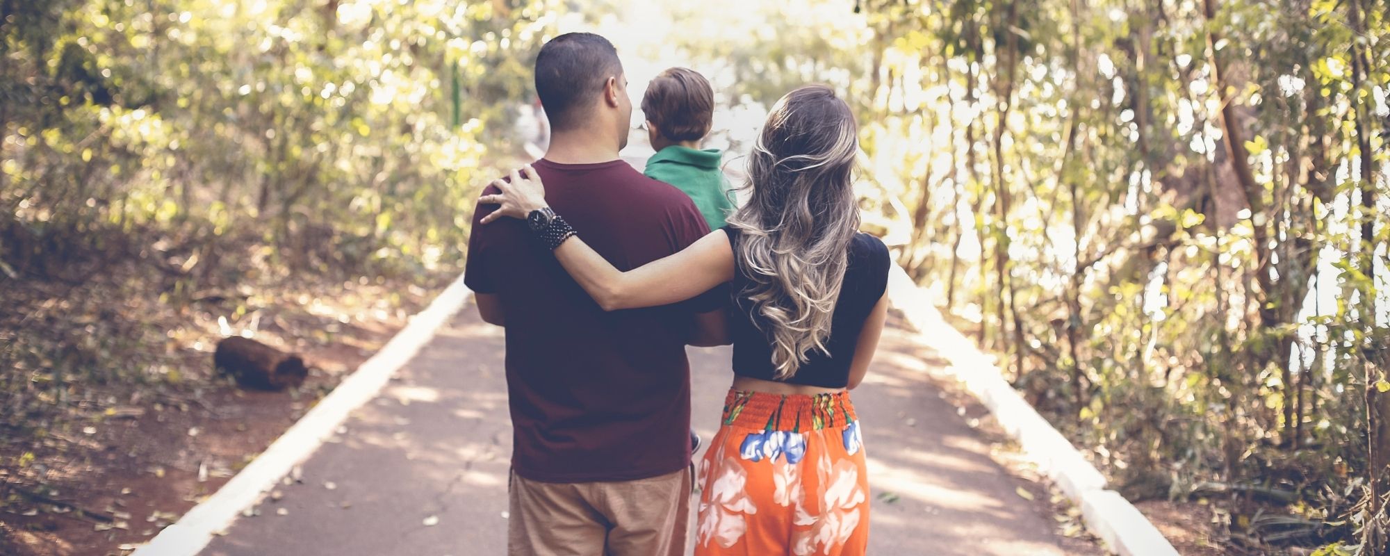 Une famille, un père un enfant et une mère qui marchent dans la forêt.