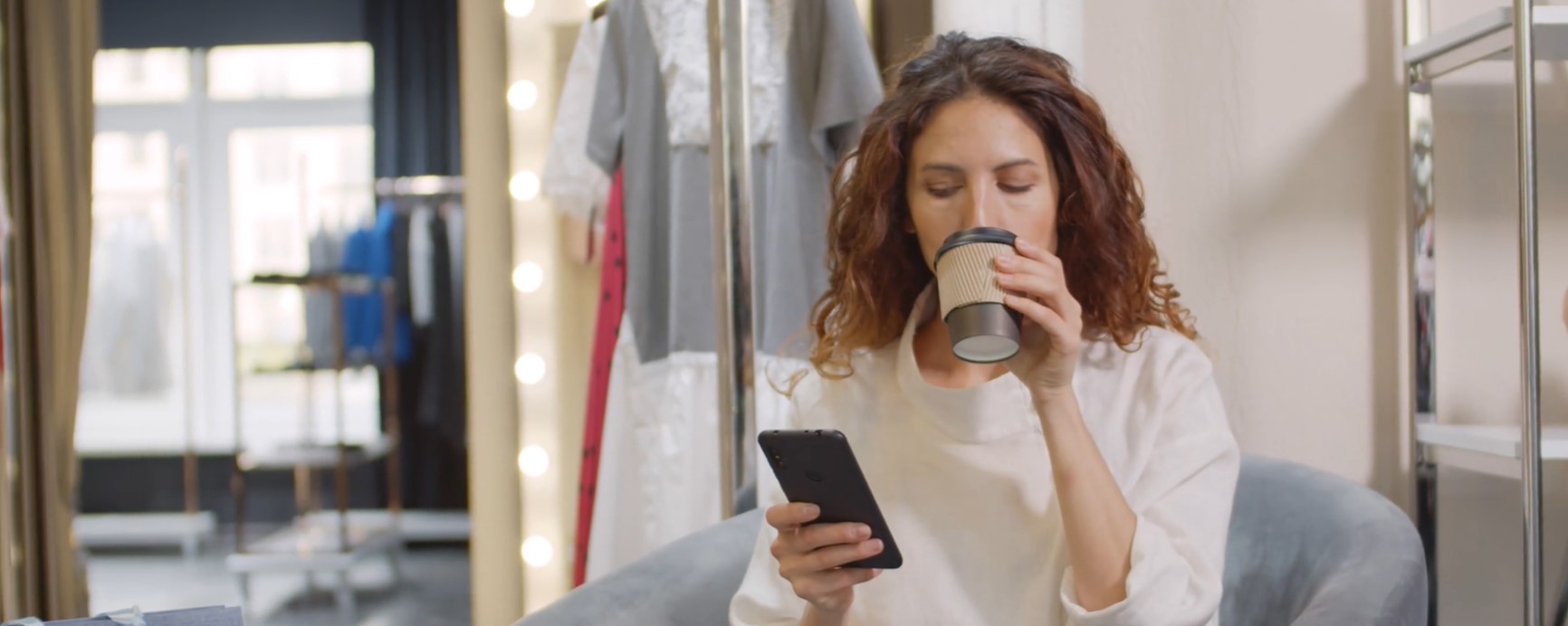 une femme boit un café en regardant son téléphone