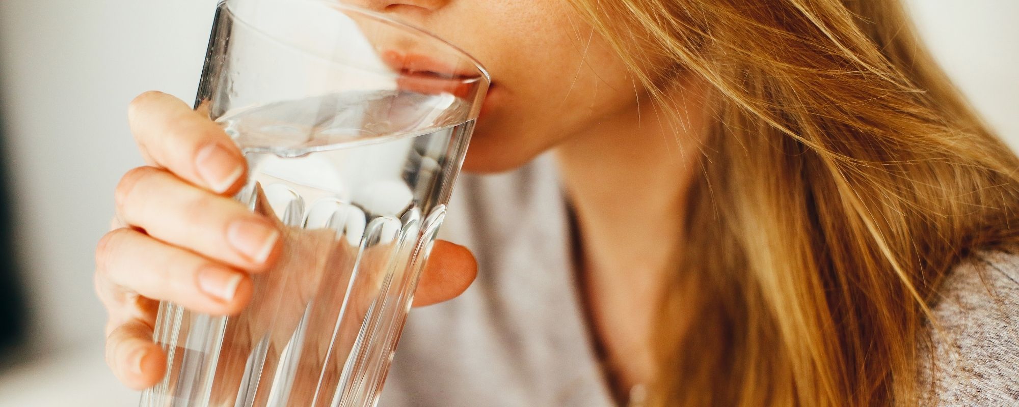 Une femme qui boit de l'eau dans un verre